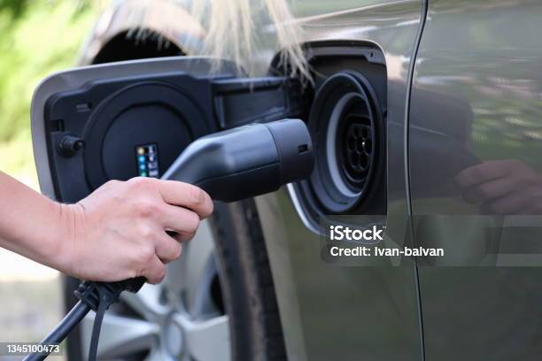 Female Hand Inserts Plug For Charging Electric Car Closeup Stock Photo - Download Image Now