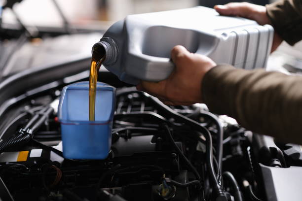 istock Locksmith mechanic pours engine oil into plastic container on motor engine 1345101225