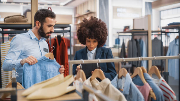 istock Clothing Store: Businesswoman Uses Tablet Computer, Talks to Visual Merchandising Specialist, Collaborate To Create Stylish Collection. Small Business Fashion Shop Sales Manager Talks to Designer. 1345105845