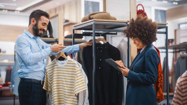 istock Clothing Store: Businesswoman Uses Tablet Computer, Talks to Visual Merchandising Specialist, Collaborate To Create Stylish Collection. Small Business Fashion Shop Sales Manager Talks to Designer. 1345105847
