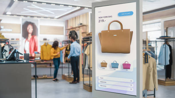 aufnahme eines bodenstehenden lcd-touchscreen-displays mit benutzeroberfläche des online-bekleidungsgeschäfts, das im bekleidungsgeschäft steht. self-service-checkout. diverse menschen in modischen geschäften, die kleidung kaufen. - selbstbedienung stock-fotos und bilder