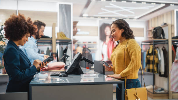 Clothing Store Checkout Cashier Counter Woman And Male Retail Sales  Managers Accept Nfc Credit Card Payment From A Young Stylish Female  Customer For New Stylish Clothes Stock Photo - Download Image Now -