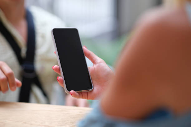 istock Woman holding mobile phone at table in bar closeup 1345107613