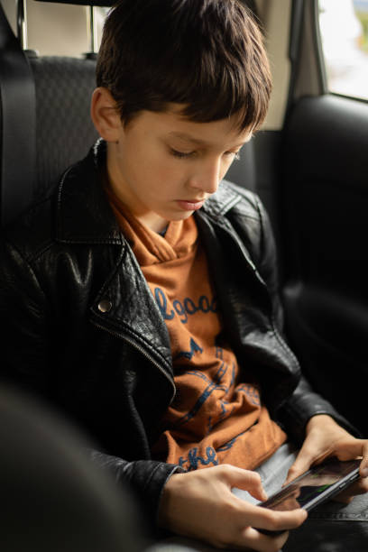 istock Passenger Teenage Boy in car using smart phone on Back Seat 1345108361