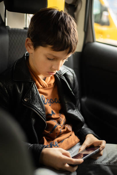 istock Passenger Teenage Boy in car using smart phone on Back Seat 1345108366