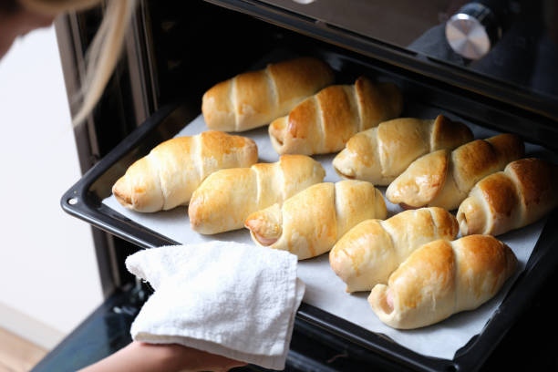 istock Woman chef taking out baking sheet with delicious buns from oven closeup 1345108458