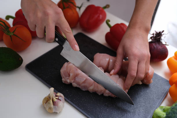istock Chef cutting meat with kitchen knife at table with vegetables closeup 1345108508