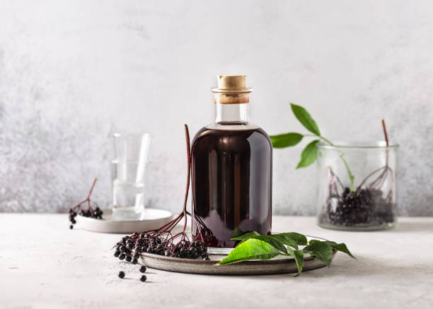 Delicious black elderberry liqueur in a glass bottle. Delicious black elderberry liqueur in a glass bottle. Homemade food concept. Copy space. sambucus nigra stock pictures, royalty-free photos & images