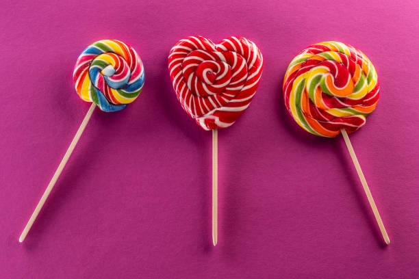 Set of three lollipops with rainbow colour and fruit flawor with purple background.