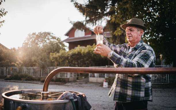 Mature man distills brandy Traditional homemade distillery for making brandy serbian raki stock pictures, royalty-free photos & images