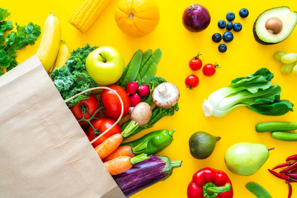 bolsa con frutas y verduras sobre fondo amarillo - paper bag fotos fotografías e imágenes de stock