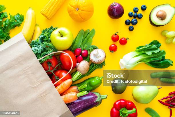 Bag With Fruits And Vegetables On Yellow Backdrop Stock Photo - Download Image Now - Paper Bag, Spilling, Blueberry