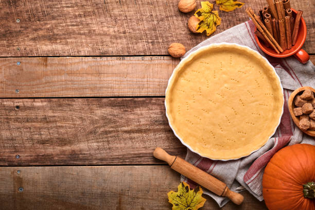 istock Dough for baking quiche, tart or pie in ceramic baking form ready for bake on kitchen towel over old rustic plank wooden background. Top view, copy space. Concept homemade baking for holiday. 1345115752