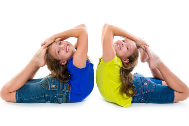 twin kid sisters symmetrical flexible playing happy twin kid sisters symmetrical flexible playing happy on white background acrobatic gymnastics stock pictures, royalty-free photos & images