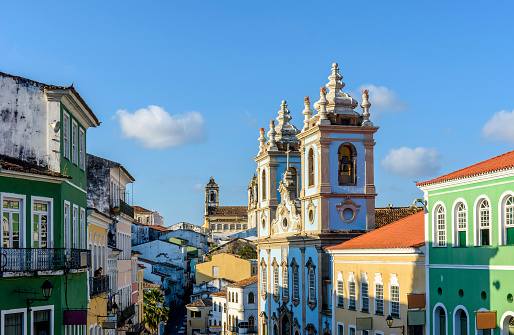 Colorful and ancient colonial houses facades and historic church towers in baroque and colonial style with blue sky in the famous Pelourinho district of Salvador, Bahia