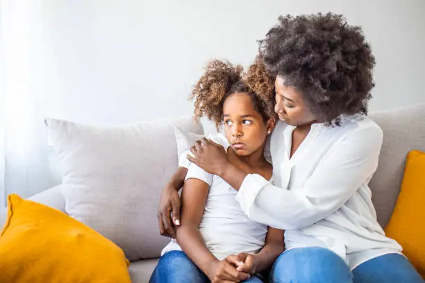 Photo of Loving worried mom psychologist consoling counseling talking to upset little child girl