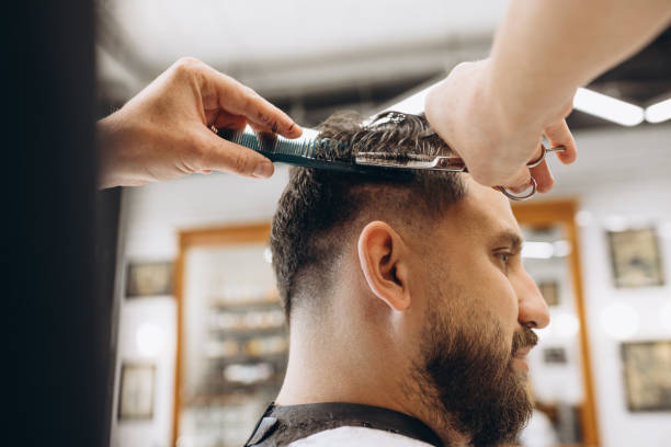 istock Man getting haircut at the barbershop. Professional barber at work process. Beauty, selfcare, style, fashion, healthcare and male cosmetics concept. 1345125708