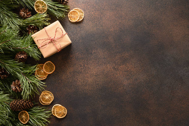 istock Christmas gift, aroma orange chips, fir tree and cones on brown background. 1345125781