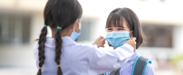 Children students in student uniform wearing protective face mask for each other to go to school after COVID-19 pandemic situation getting better. Back to School Concept Stock Photo stock photo