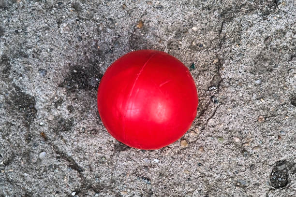 Red plastic ball against the background of a natural stone surface close-up.