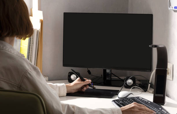 istock Woman using graphics pad to retouching.Computer monitor,keyboard,drawing tab,lamp on the white office desk.Empty space 1345127949