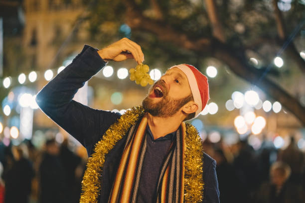 mann isst traube an silvester in spanien - zwölf uhr stock-fotos und bilder