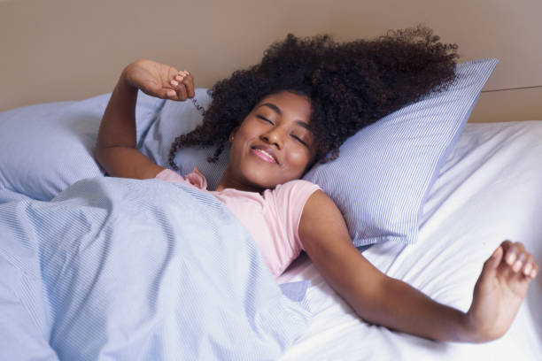 mulher afro-americana esticando na cama de manhã - wake up stretching women black - fotografias e filmes do acervo