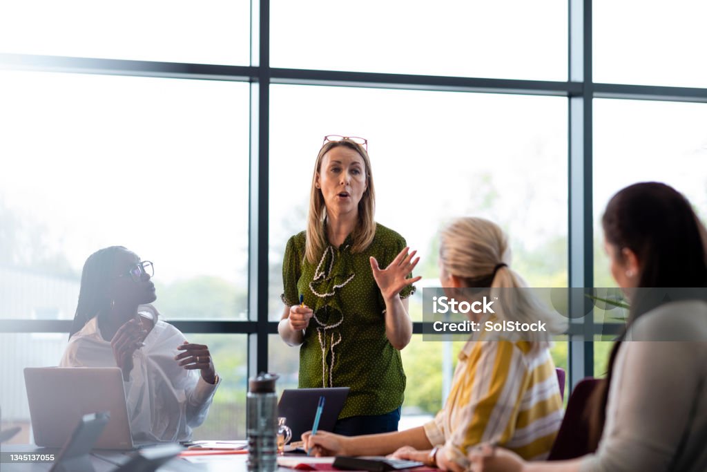 Boardroom Business Meeting A wide angle view of a group of female colleagues in a boardroom in their office. They are having a meeting together and are using technology for the presentation. The office is in Hexham in the North East of England. Strategy Stock Photo