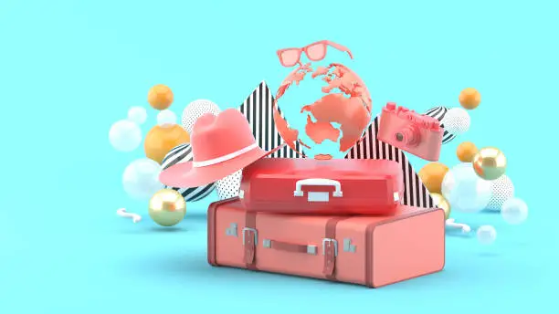 Photo of A suitcase under the globe surrounded by a camera and hat on an blue background.-3d rendering.