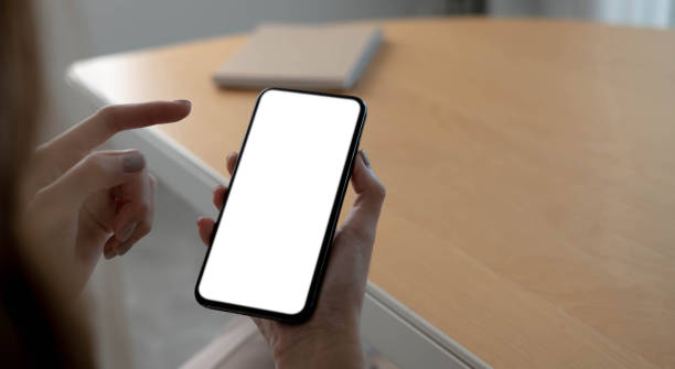 istock Mockup image blank white screen cell phone.women hand holding texting using mobile on desk at home office. 1345137888