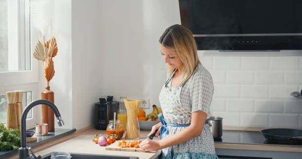 istock Young woman cutting tomatos in nice kitchen for pasta sauce 1345144176
