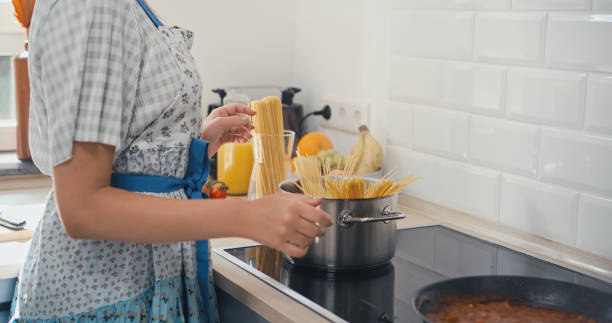 istock Young woman putting spaghettis in boiling water 1345144517
