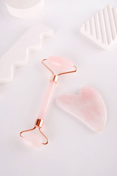 istock Pink face roller and gua sha massager made from natural  quartz  stone over white background.  Lifting and toning treatment at home. 1345144841