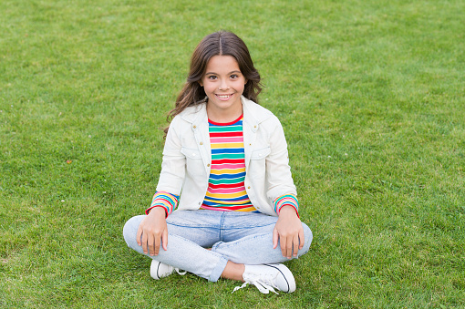 Relax at school yard. Kid relaxing outdoors. Peace of mind. School break for rest. Adorable pupil. Girl kid sit on lawn. Girl school uniform enjoy relax. Importance of relaxation. Little schoolgirl.