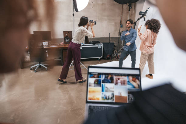 Photographer and her team working in a fashion studio Business team working in a photographic studio to portray a couple of models. Attending to the shoot models, creative directors and a stylist. photo studio model stock pictures, royalty-free photos & images