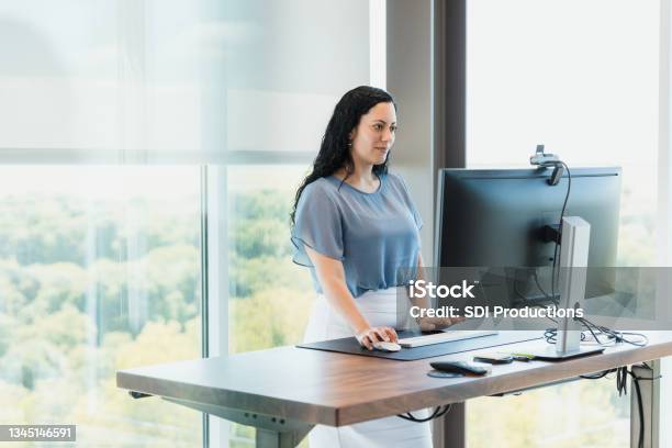 Using Standing Desk Female Ceo Works In Corner Office Stock Photo - Download Image Now