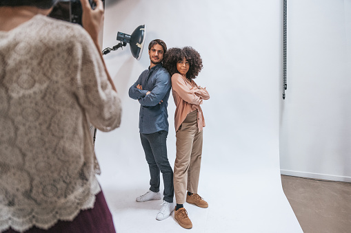 Business team working in a photographic studio to portray a couple of models. Attending to the shoot models, creative directors and a stylist.