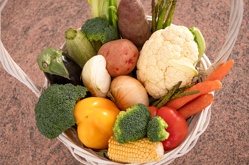 White basket with fresh vegetables, broccoli, pepper, caulifrolower, tomatoes. Healthy eating concept and detox diet. Vegan and vegetarian food.