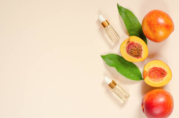 istock Two bottles with oils and fresh peaches on a delicate beige background, copy space. Natural oils for skin and hair care 1345149217