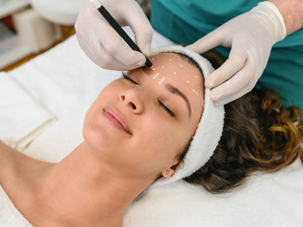 istock Beautician draw correction lines on woman face 1345155652