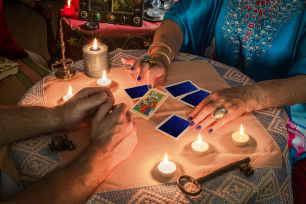 istock Fortune teller showing a Tarot card to a costumer on a table with lit candles 1345157871