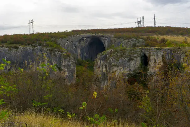 Photo of Panoramic view of entrance of Prohodna cave also known as God's eyes near Karlukovo village, Bulgaria. Colorful cave formation with giant entrance.