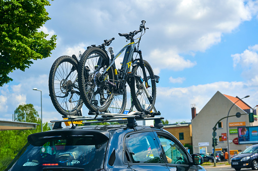 Berlin, Germany - July 3, 2021: Car with a bike carrier attached on the top and two bicycles mounted on it.