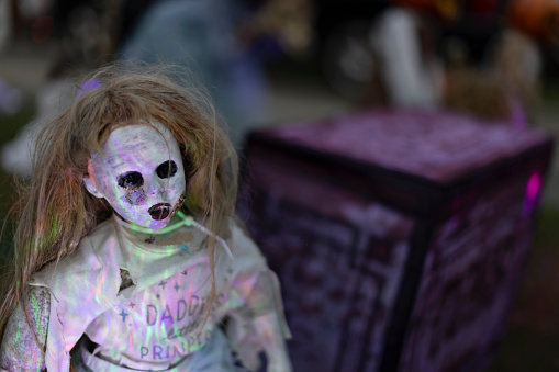 Creepy doll wearing Daddy's Little Princess shirt is part of a residential yard's Halloween decor