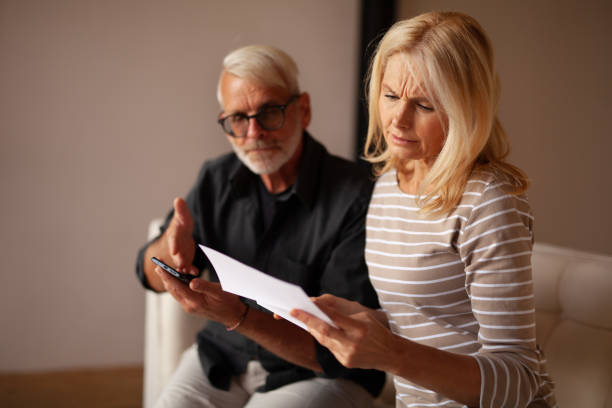 Unforeseen expenses. A mature married couple learns about bankruptcy, the minimum cash payment. Frustrated by the expensive utility bill Unforeseen expenses. A mature married couple learns about bankruptcy, the minimum cash payment. Frustrated by the expensive utility bill. unusual couple stock pictures, royalty-free photos & images