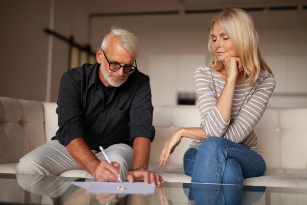 the severance of relations between an mature man and a woman. signing a document for divorce. difficulties in family relationships - divórcio imagens e fotografias de stock