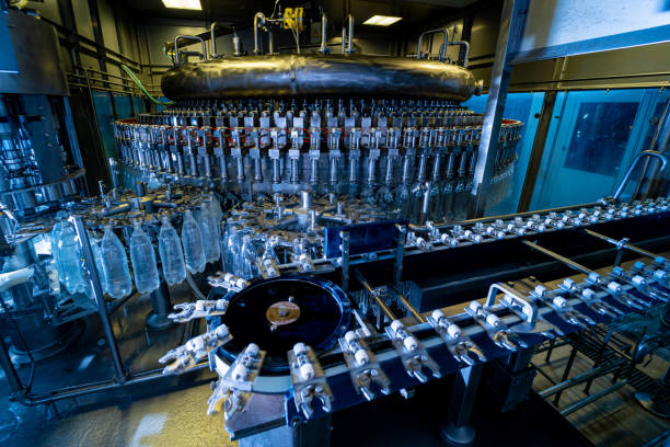 la machine de remplissage automatique verse de l’eau dans des bouteilles en plastique pet dans une usine de boissons moderne. - bottling plant brewery industry food photos et images de collection
