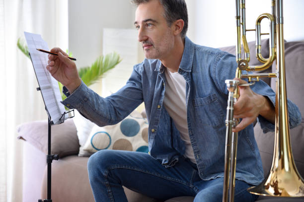 tromboniste faisant des annotations sur une partition s’entraînant à la maison - privacy partition photos et images de collection