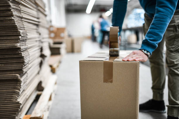 männlicher arbeiter taping cardboard box - schiffsfracht stock-fotos und bilder