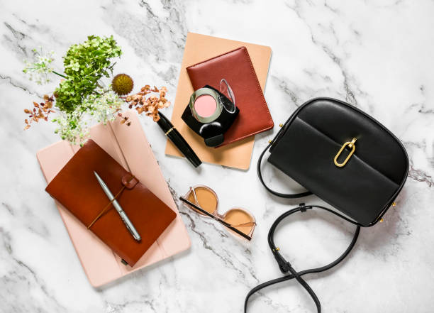 istock Women's office desktop - notebooks, organizer, tablet, cross body black leather bag on a marble background, top view 1345170583